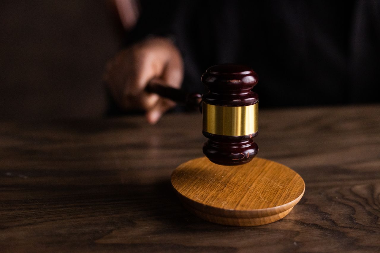 Services A gavel striking a sound block, symbolizing justice and legal authority in a courtroom setting.