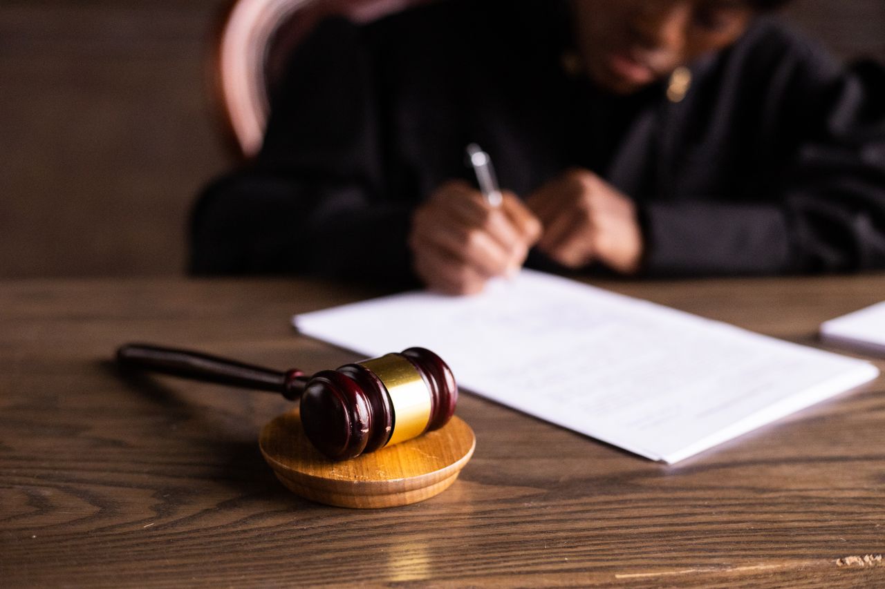 Services Judge signing documents at desk with focus on gavel, representing law and justice.